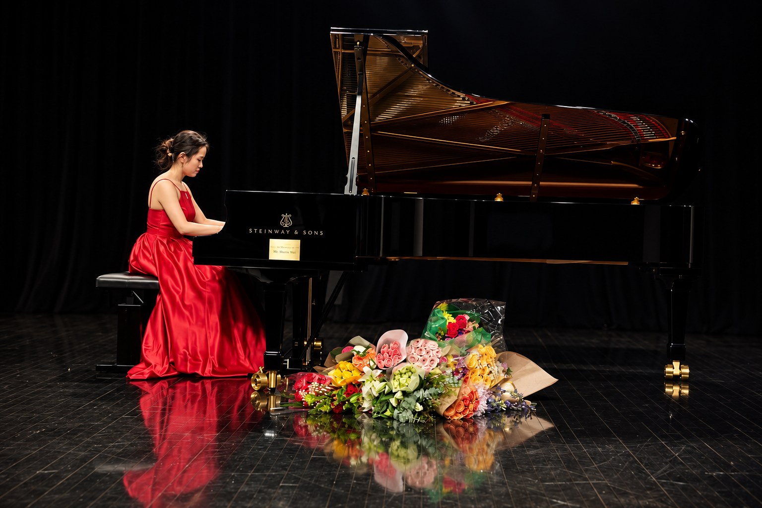 Mary in a red gown performing beside flowers and a grand piano